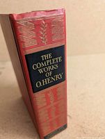 Spine of red cloth hardcover showing title, decorative motifs, publisher block