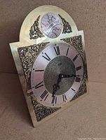 Front view of brass faceplate showing dial, numerals, Tempus Fugit medallion, ornate corners