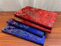 Stack of three silk brocade journals showing red and blue covers