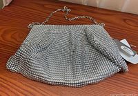 Front view of silver beaded mesh purse with chain strap displayed on wooden surface