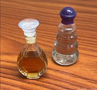 Two miniature perfume bottles side by side on wood surface