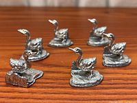 Six pewter swan place card holders on wood surface