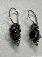 front view of both earrings displaying garnet cabochons and grape motif