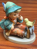 Front angled view of figurine showing boy, bird, colors, base
