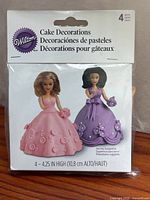 Front of sealed Wilton package showing two princess cake topper designs and 4-piece count