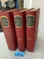 Front view of three red hardcover volumes showing titles and volume identifiers on spines