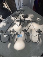 All three metal double-arm wall candle sconces on table
