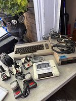 Overall view: C64 computer, datasette, joysticks, power supplies, cables, partial disk drive