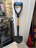 Full view of compact camping shovel leaning against wall