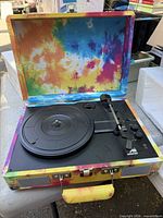 Turntable open showing platter, tonearm, controls and interior tie-dye lining