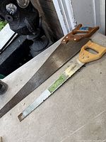 Both saws laid on tabletop showing full blades and wooden handles