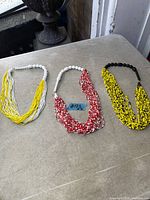 Front view of all three necklaces laid flat showing colours and strand style
