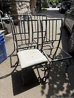 Four matching cast aluminum chair frames on driveway