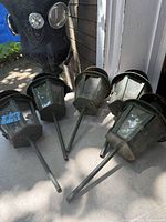 All five metal lantern tea light holders with stakes visible, noting one glass defect
