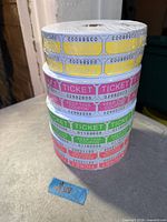 Stack of four double-roll raffle ticket rolls showing colours and numbering