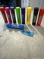 Group of nine Studio quick-dry paint sticks standing and one lying to show labels