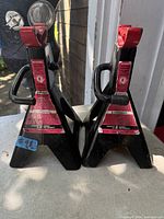 Both axle stands upright showing red posts, labels, and overall condition