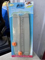 Front view of sealed 10 inch paper trimmer package showing product details and extra blade
