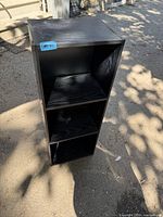 Front view of black three-shelf side cabinet showing open shelves and wood-grain finish