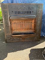 Full view of cast iron electric fireplace insert front showing decorative relief and heating element bars