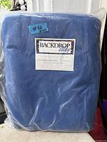 Front view of sealed Backdrop Alley chromakey blue muslin backdrop showing label and packaging