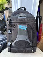 Front view of Lowepro black camera sling backpack showing pockets, straps and ID window