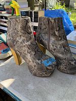 Front and side view of both ankle boots showing snakeskin pattern, wooden heels, size label tape