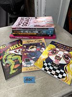 Stack of nine graphic novels and indie comics front and top view