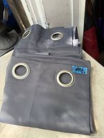 Folded grey drape panels with metal grommets visible