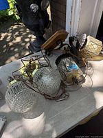 Two wall sconces with wood backplates and diamond-pattern glass shades lying on table