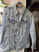 Front view of light wash True Religion denim jacket on hanger