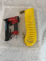 Arrow PT50 staple gun and coiled yellow air hose side by side