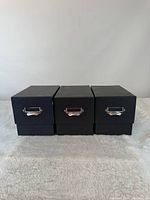 Three closed black CD storage boxes showing exterior and handles