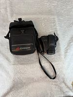 Camera with strap alongside branded carry case