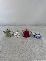 All four miniature teapots lined up for scale and style comparison