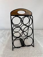 Front view showing six circular bottle holders and wood handle