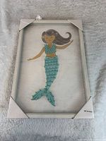 Full view of framed mermaid string art with corner protectors