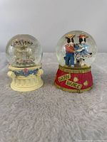 Front view showing both cow and cherub musical snow globes