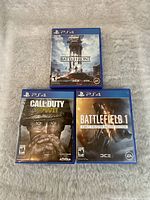 Front covers of three PS4 game cases: Star Wars Battlefront, Call of Duty: WWII, Battlefield 1 Early Enlister Deluxe Edition
