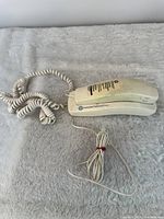 Full view of phone with coiled cord and line cord on fabric surface
