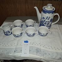 Group shot of coffee/tea pot with lid, creamer and six cups