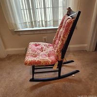 Side view of dark brown wood rocking chair with red toile cushion