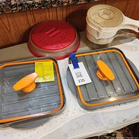 Lot overview showing grey/orange trays, red cover, stacked handled steamers