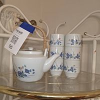 Teapot with lid and six cups on shelf