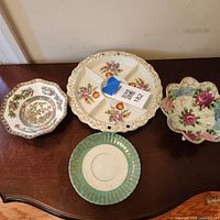 All four porcelain/ceramic pieces displayed together on table