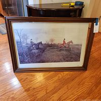 Full view of framed print on floor showing artwork, frame, and glass