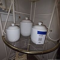 three white canisters with lids on shelf