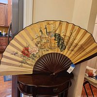 Full view of oversized folding fan on table showing design and size