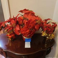 Three artificial poinsettia plants displayed on table