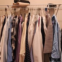 Full view of closet rod with approximately 15 shirts of various styles and colors